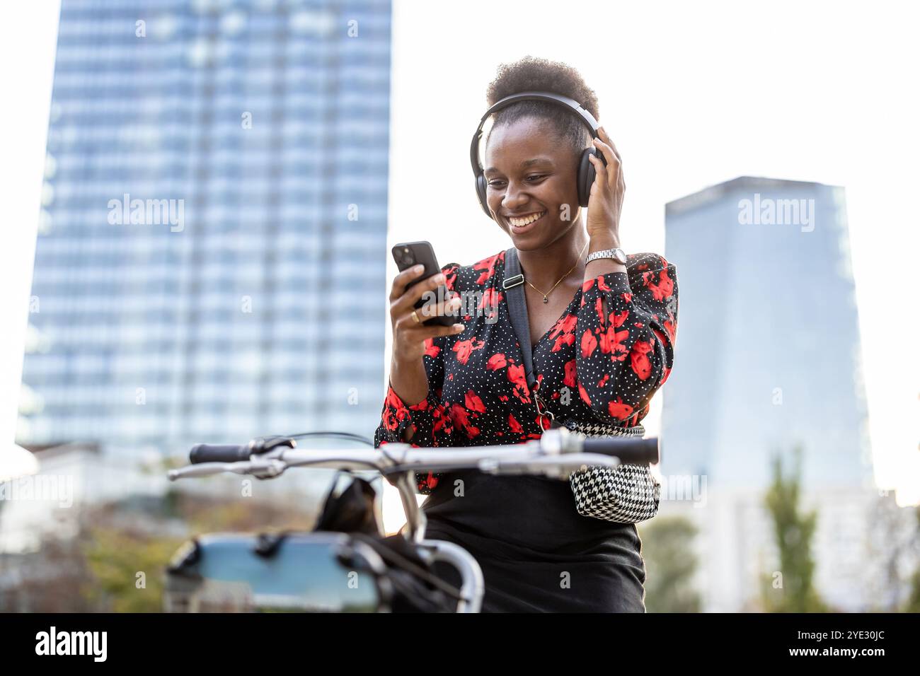 Ritratto di una giovane donna sorridente con la sua bicicletta in città Foto Stock