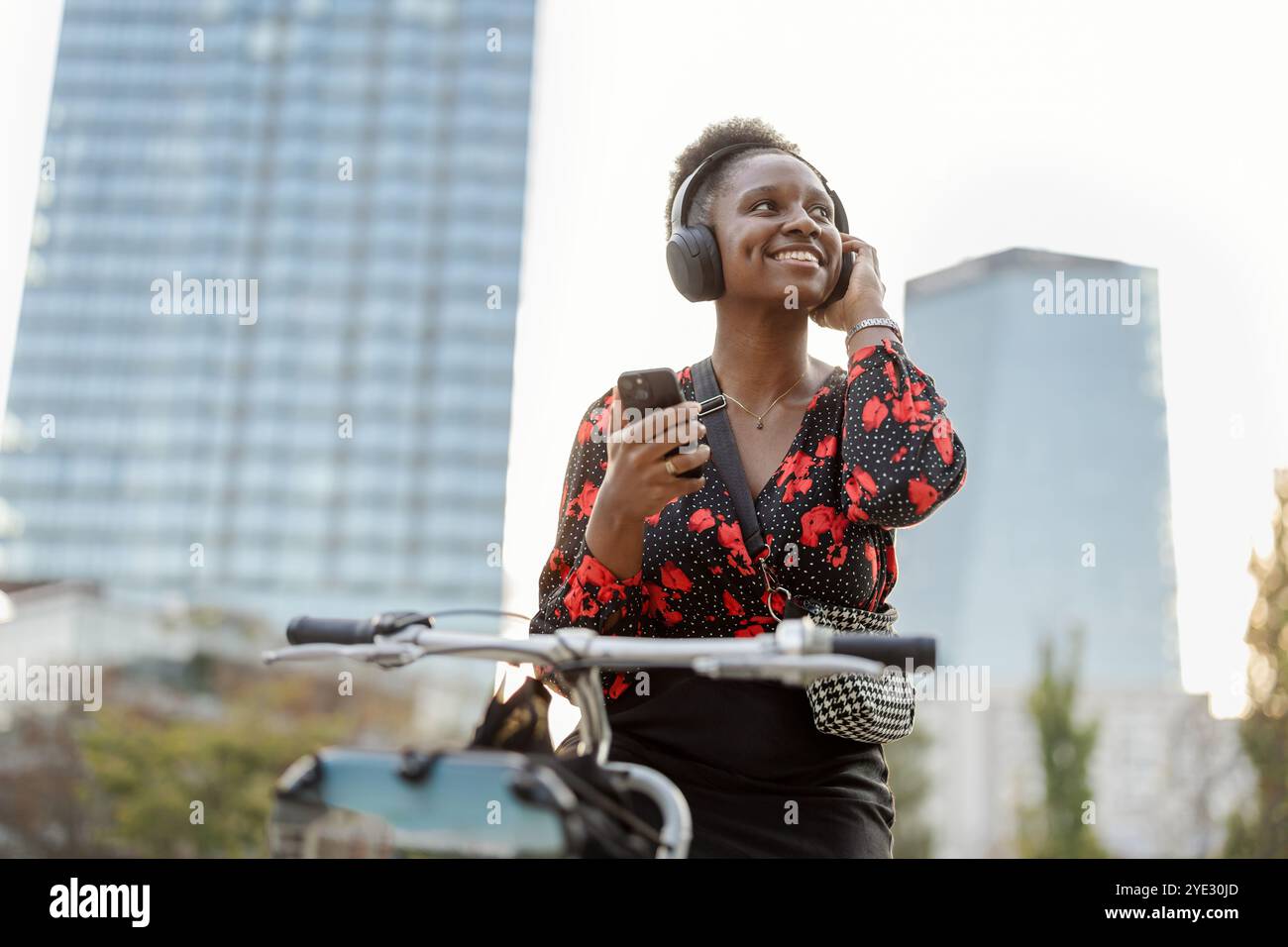 Ritratto di una giovane donna sorridente con la sua bicicletta in città Foto Stock