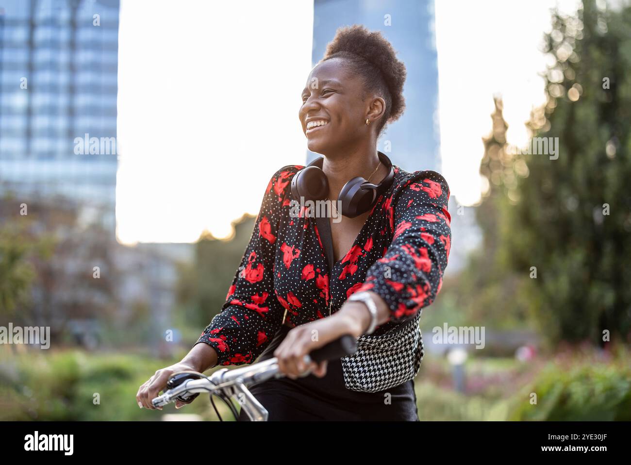 Ritratto di una giovane donna sorridente con la sua bicicletta in città Foto Stock