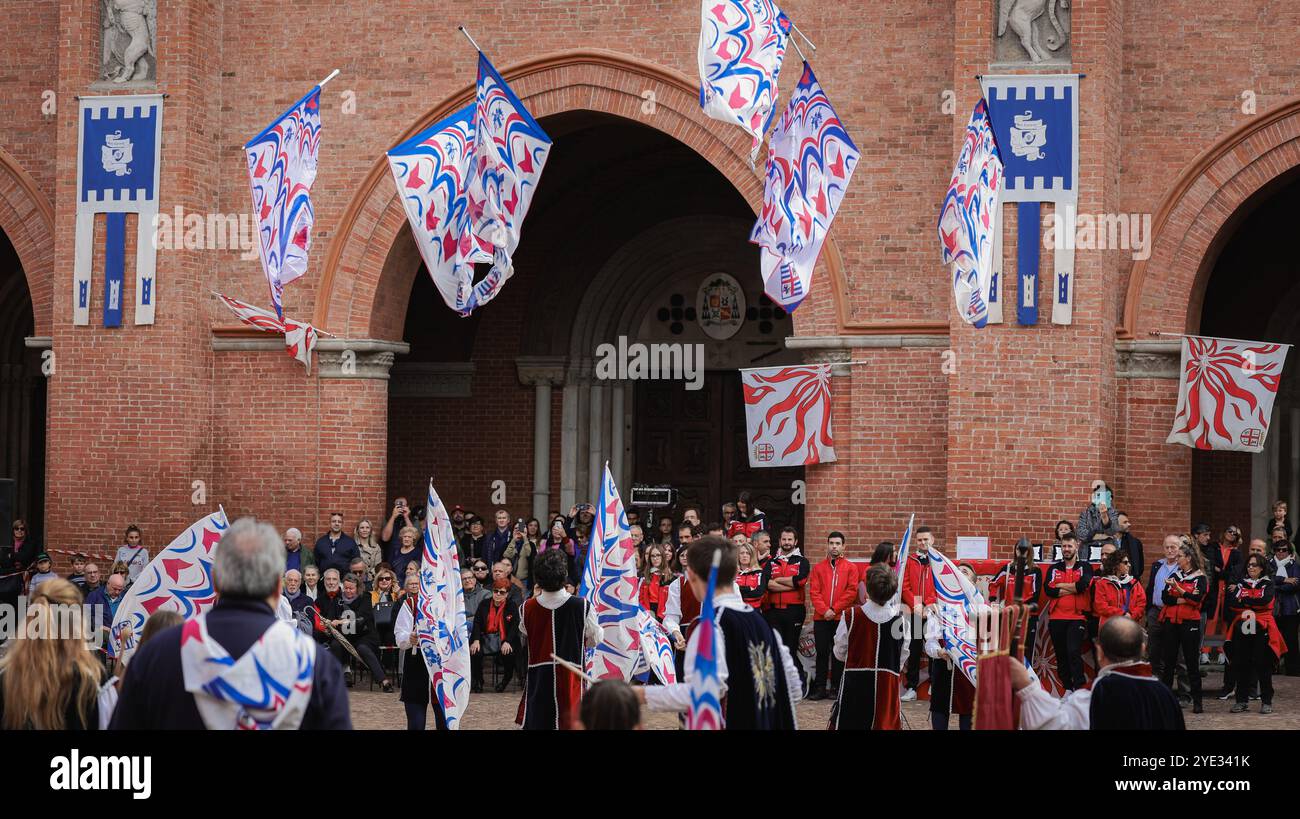 I partecipanti sventolano bandiere e indossano costumi tradizionali in un vivace festival ad Alba, Italia. L'evento mette in mostra la cultura locale e attira una folla di persone Foto Stock