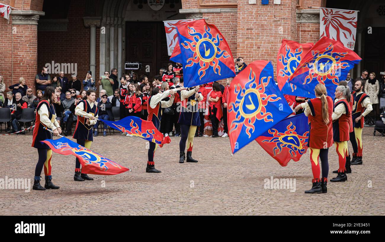 Gli artisti sventolano elegantemente bandiere vibranti mentre intrattenono un pubblico vivace ad Alba Italia. Questo evento festivo mette in mostra le tradizioni e l'arte locali Foto Stock