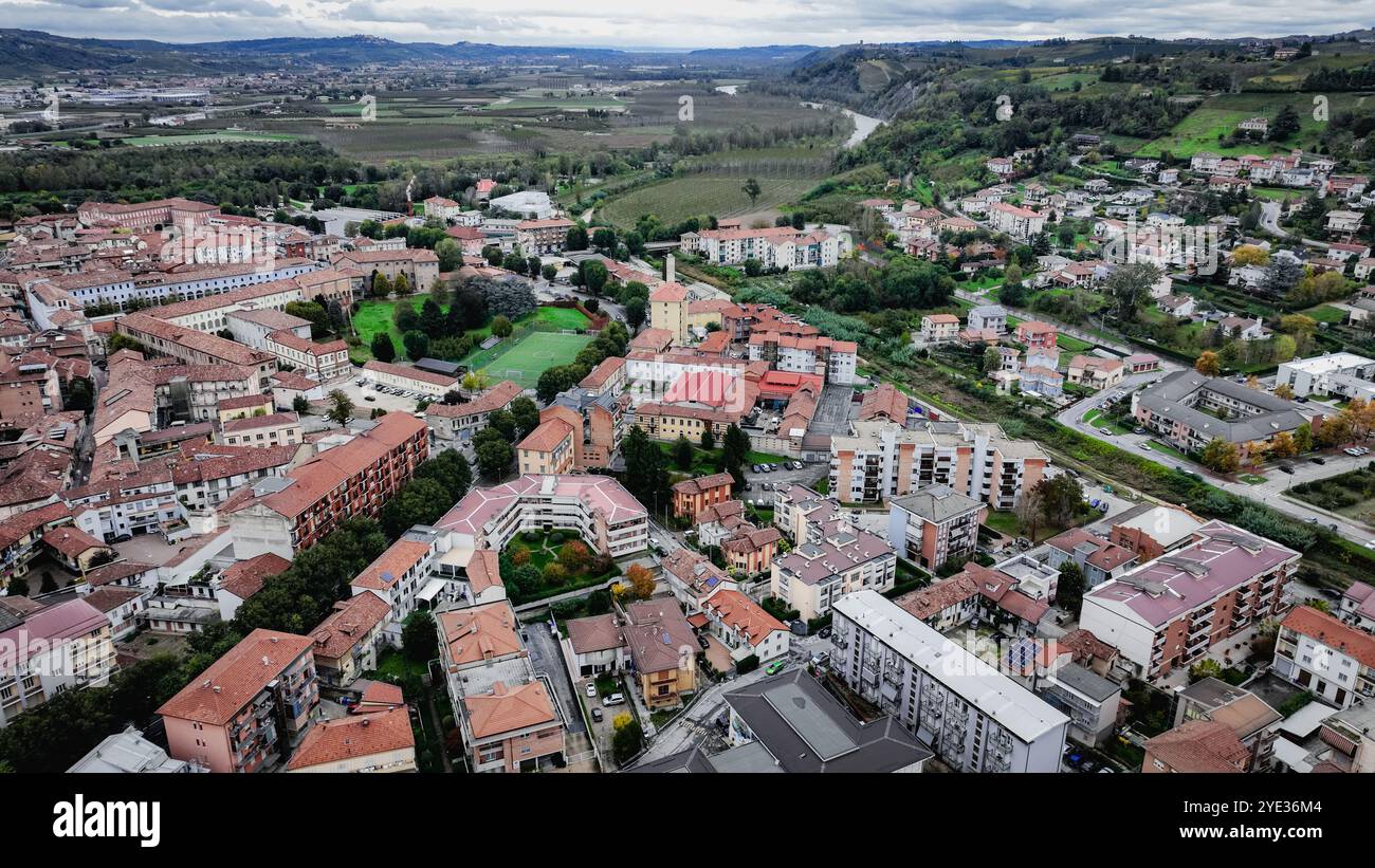 Una prospettiva aerea cattura la pittoresca cittadina di Alba, in Italia, mettendo in evidenza la sua architettura unica e gli splendidi paesaggi verdi contro una nuvola Foto Stock