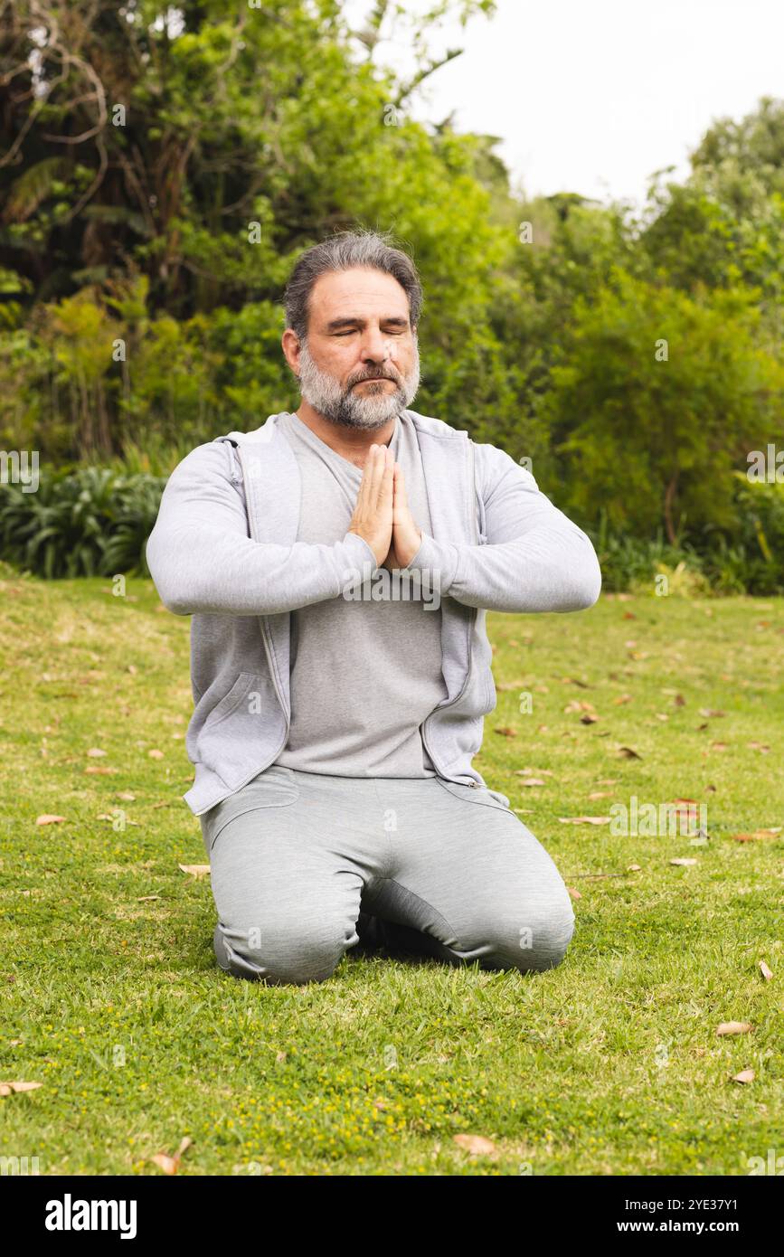 Meditare in giardino, uomo maturo che pratica consapevolezza e relax all'aperto Foto Stock