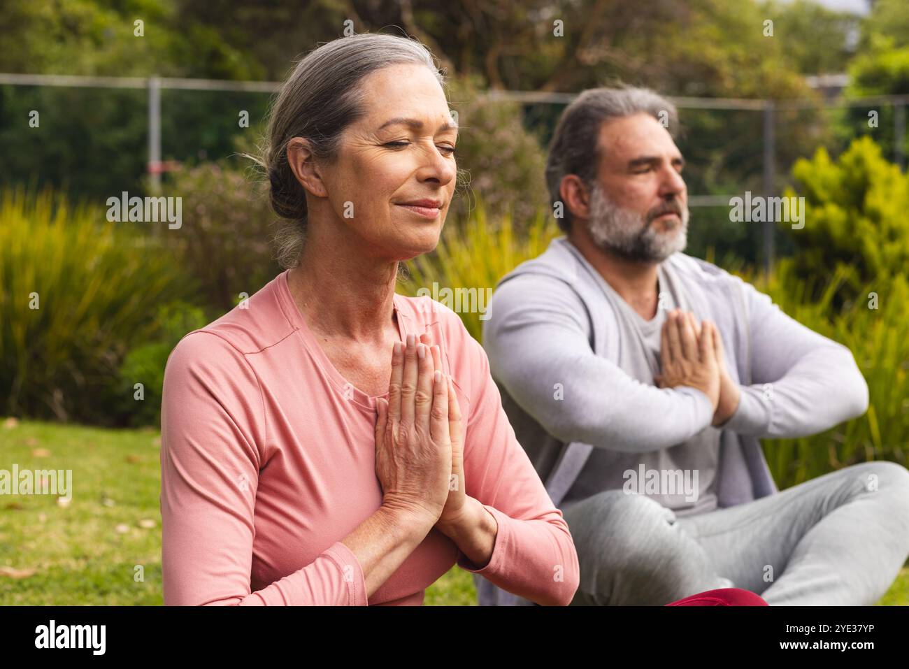 Coppie mature che meditano all'aperto, trovano pace e relax nella natura Foto Stock