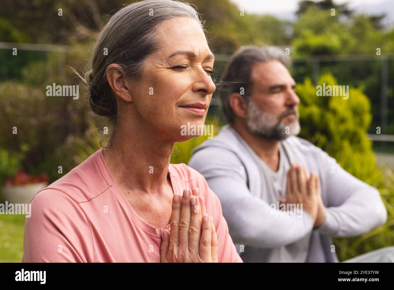 Coppia matura che meditano all'aperto, godendosi momenti tranquilli nella natura insieme Foto Stock