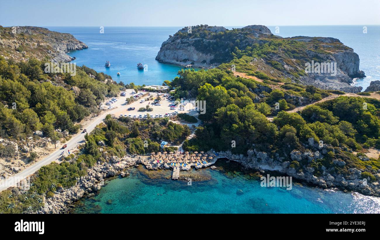 Sulla spiaggia Plaka in primo piano nella baia di Ladiko, sullo sfondo la popolare baia di Anthony Quinn sull'isola greca di Rodi. Foto Stock