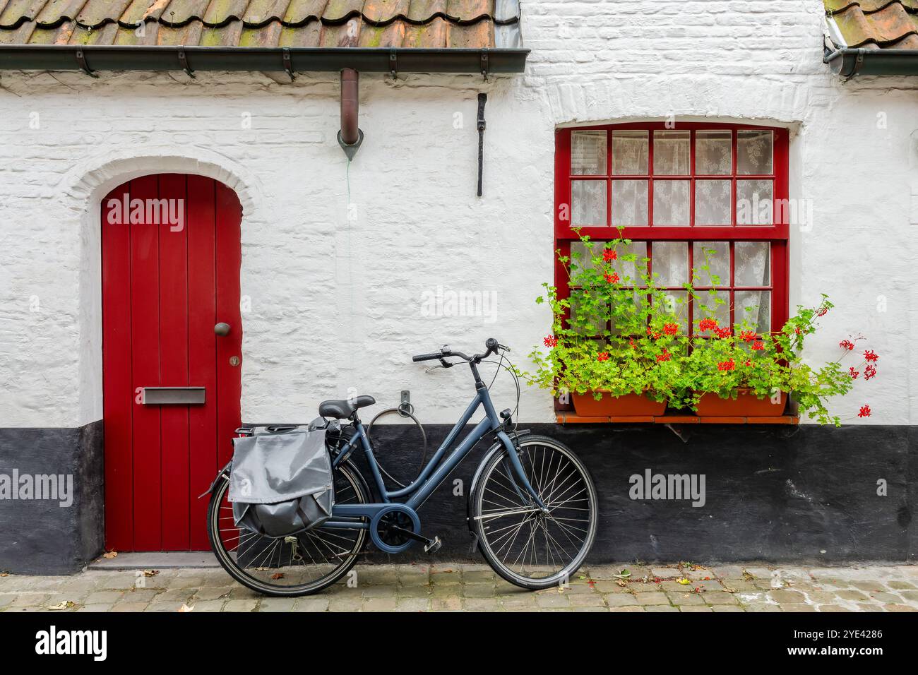 Pittoresca casa rossa e bianca con una bicicletta in una strada di Bruges, Belgio Foto Stock