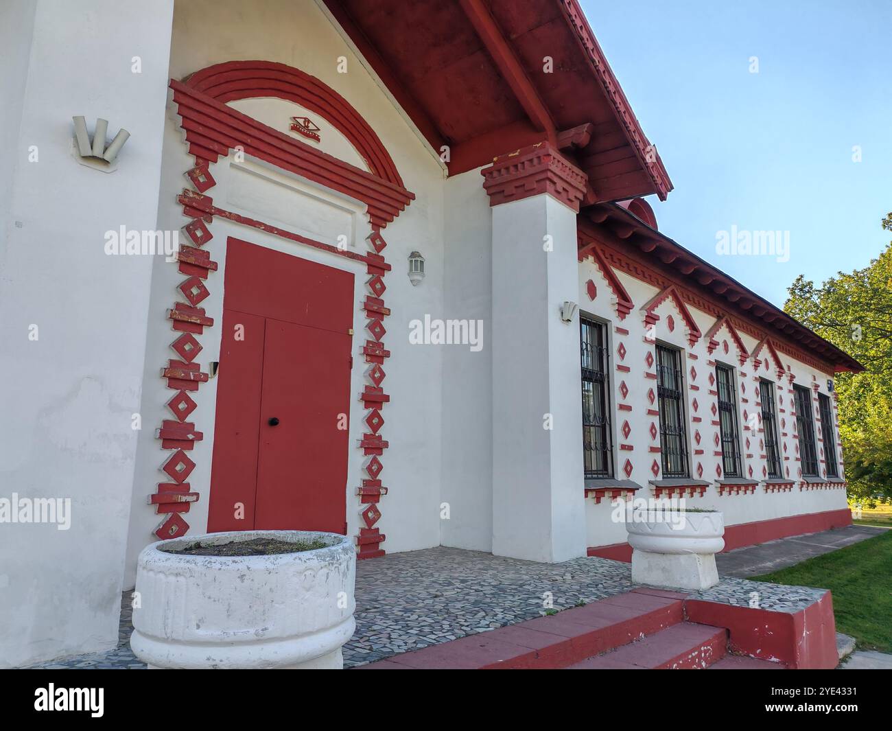 edificio pittoresco con una porta rossa e intricati mattoni, adornato da una piantatrice all'entrata. La facciata mescola fascino rustico con tradizionale Foto Stock