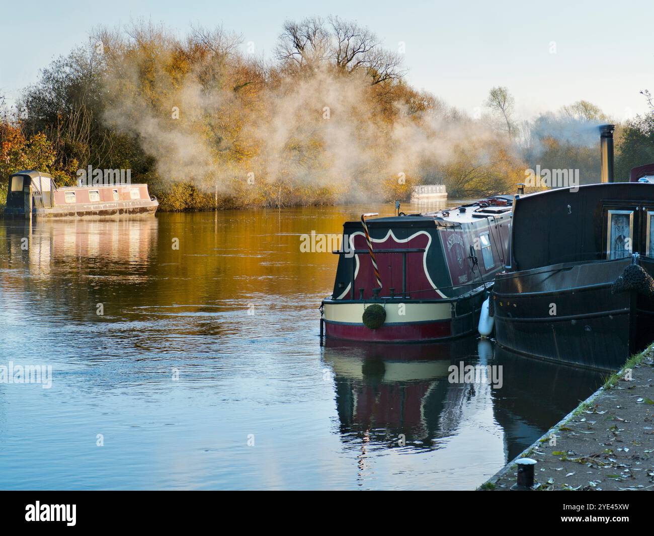 Case galleggianti ormeggiate sul Tamigi da Abingdon Lock. Abingdon-on-Thames sostiene di essere la città più antica d'Inghilterra. E il Tamigi scorre attraverso il suo cuore. In questa scena idilliaca, vedremo una vista riposante lungo il fiume da Abingdon Weir, in una mattina nebbiosa e suggestiva, appena fredda abbastanza da permettere alle barche di accendere le loro caldaie riscaldate Foto Stock