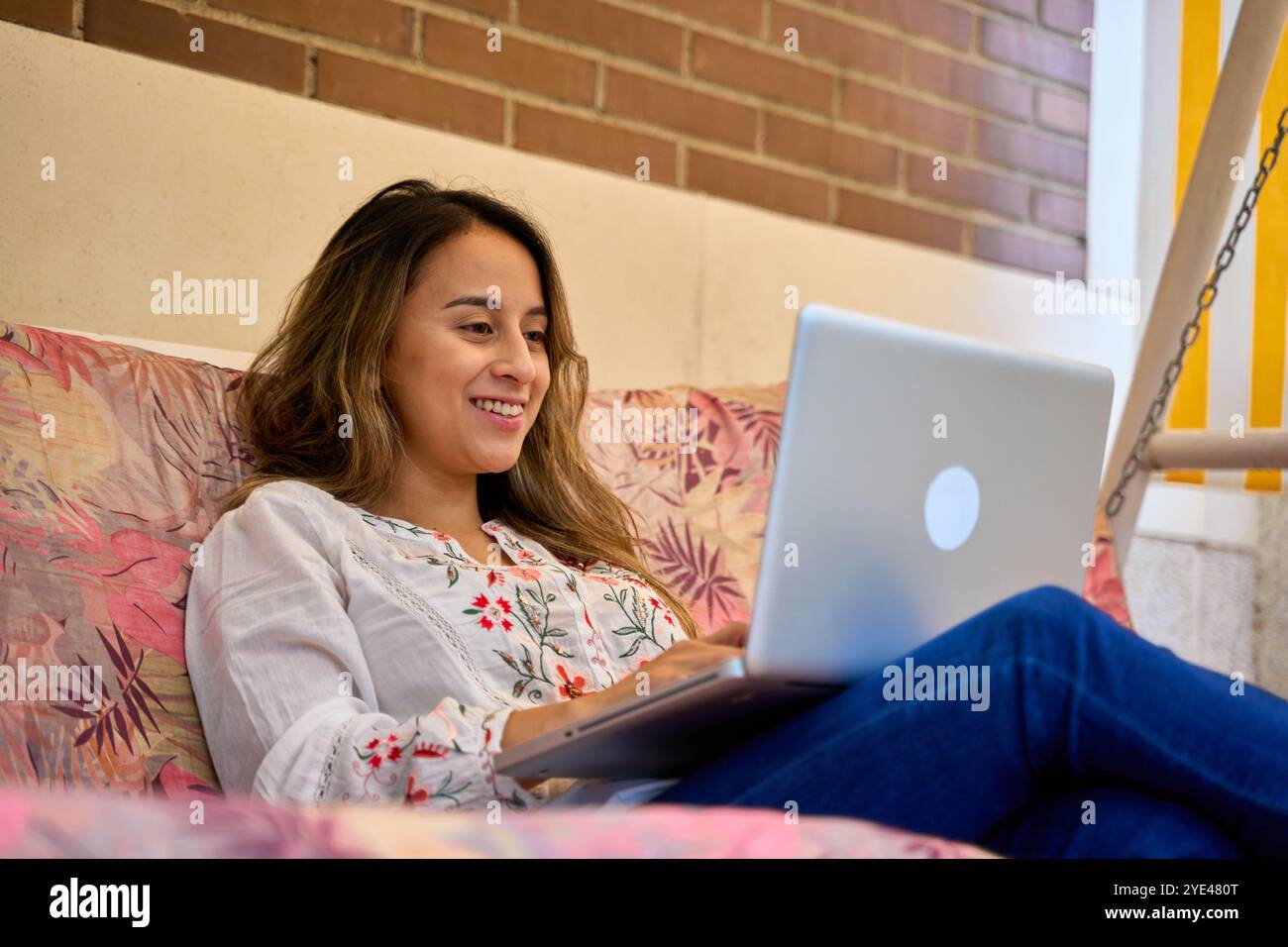 donna che riposa sul divano usando il suo computer portatile Foto Stock