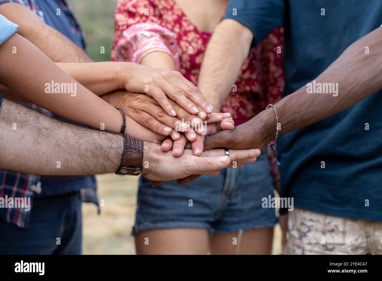 Primo piano di mani multietniche unite in cerchio, mostrando unità, lavoro di squadra e inclusione. Momento autentico di membri della comunità diversi che simboleggiano il suppor Foto Stock