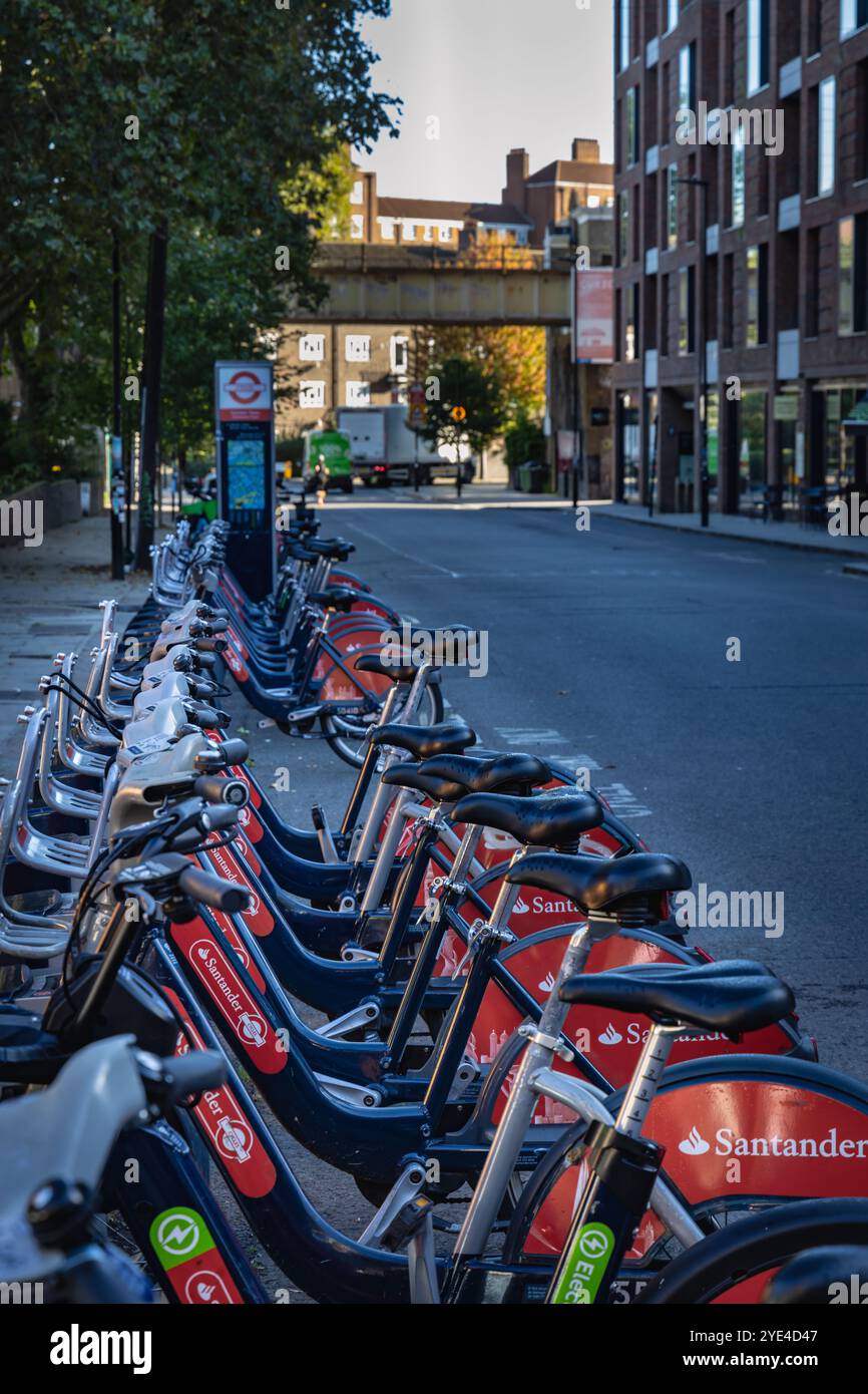 Lunga fila di biciclette Santander rosse e blu su Castlehaven Road a Camden Town, Londra. Foto Stock
