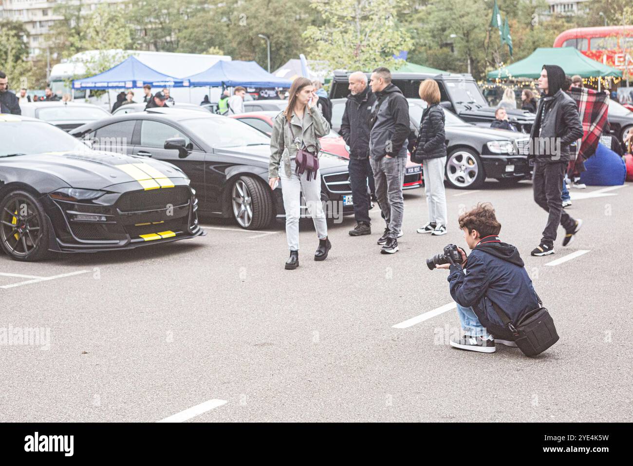 Il giovane ucraino è seduto affollato mentre fotografa le auto durante la fiera automobilistica Kyiv Car Fest di ottobre 2024 nella capitale Ucraina. Foto Stock