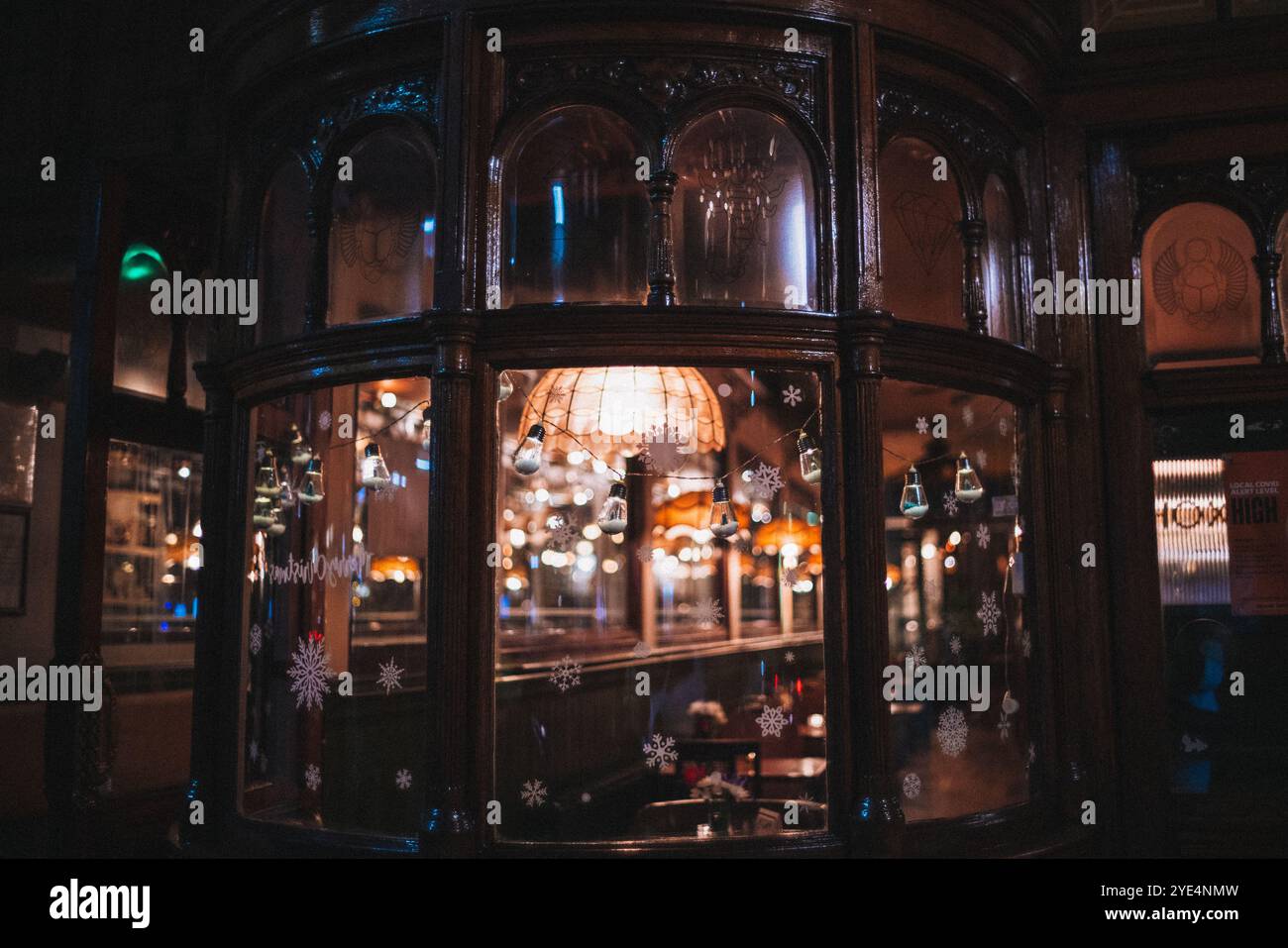 Caldo e luminoso caffè interno con decorazioni natalizie e luci da favola, visto attraverso una finestra della strada di Londra. Foto Stock
