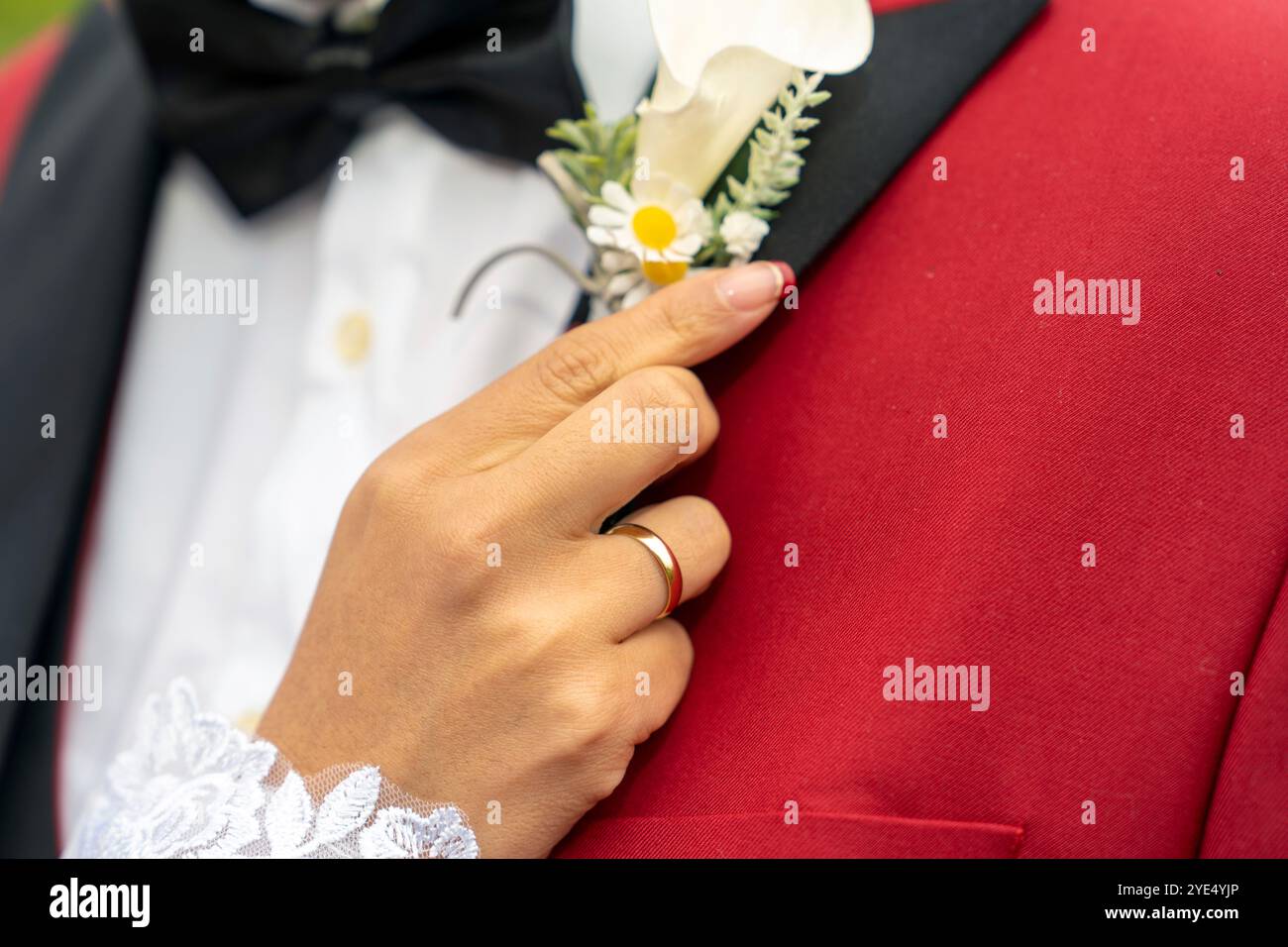 la mano della sposa colloca il fiore dello sposo Foto Stock