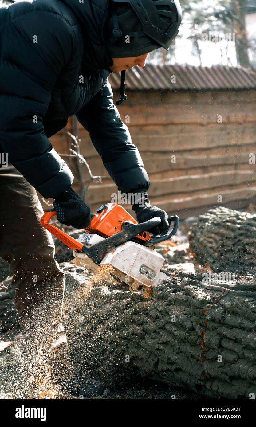 Un arborista con una motosega in mano, che segava un albero. Smaltimento degli alberi morti. Foto Stock Un arborista con una motosega in mano, che segava un albero. Smaltimento degli alberi morti. Foto Stock