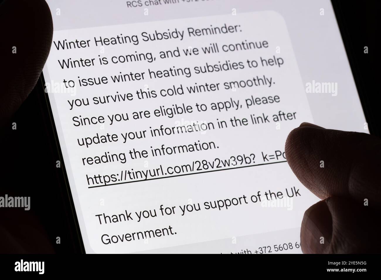 Primo piano di un vero messaggio di testo di phishing che offre falsamente sussidi per il riscaldamento invernale da parte del governo britannico, evidenziando i tentativi di frode tramite lin dannoso Foto Stock