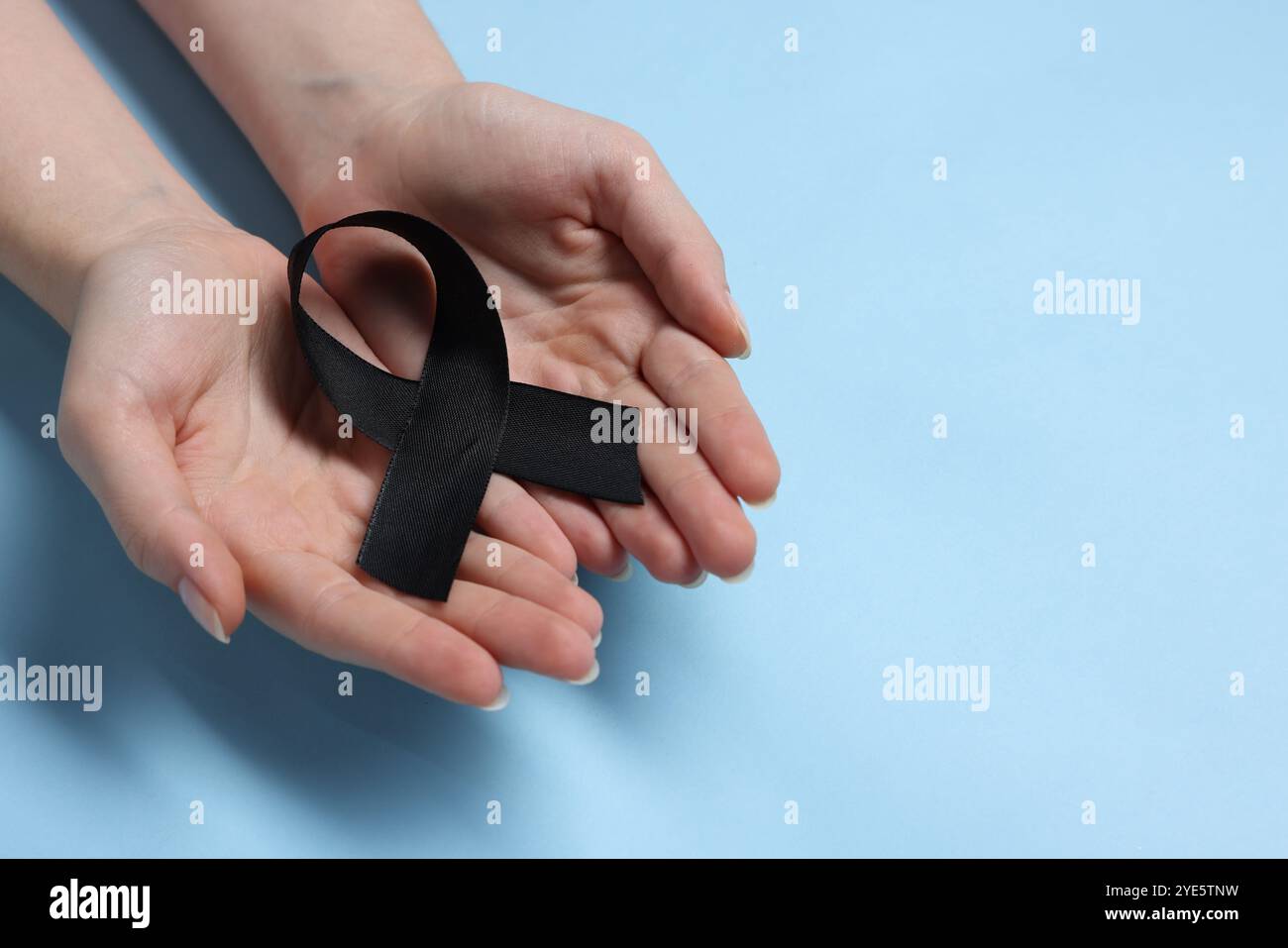 Donna con nastro nero su sfondo azzurro, primo piano con spazio per il testo. Concetto di melanoma e lutto Foto Stock