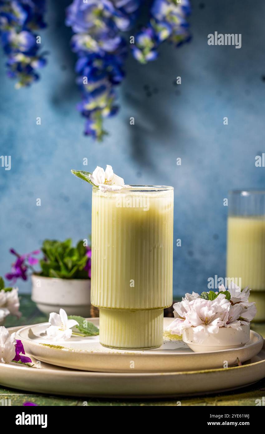 Rinfrescante latte matcha freddo decorato con delicati fiori bianchi e foglie di menta fresche, perfetto per una bevanda primaverile o estiva Foto Stock