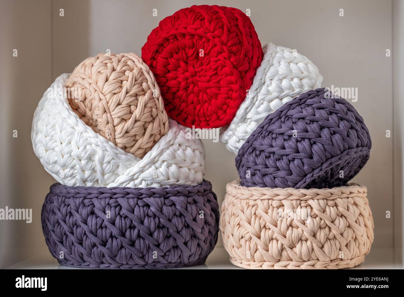 Questi cestini in tessuto finemente lavorati sono impilati in un ambiente accogliente, con un mix di colori e texture che aggiungono un tocco Foto Stock