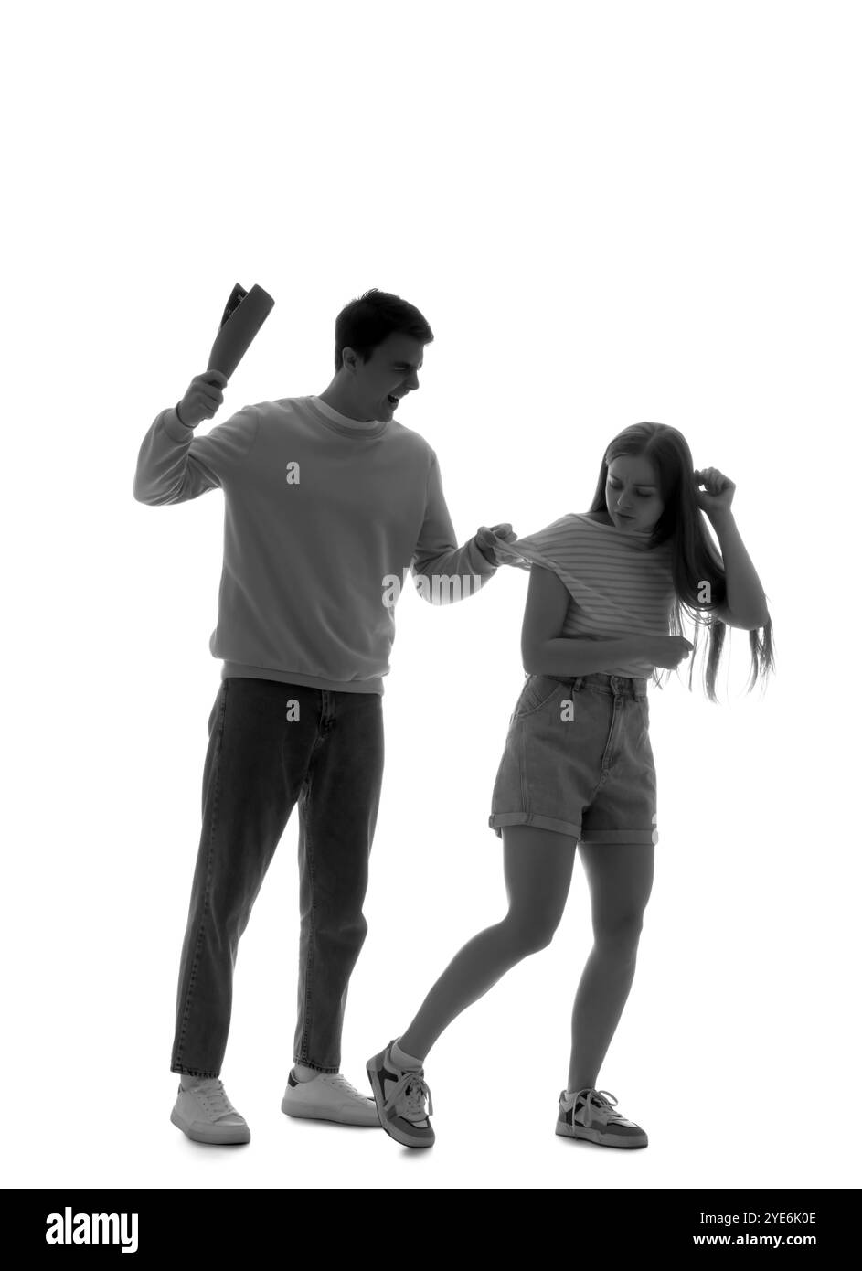Silhouette di uomo arrabbiato con rivista che fa male alla sua ragazza su sfondo bianco. Concetto di violenza domestica Foto Stock