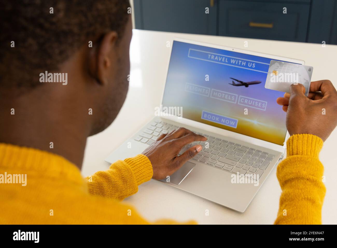 Uomo afro-americano che prenota le vacanze online utilizzando il laptop e la carta di credito a casa Foto Stock