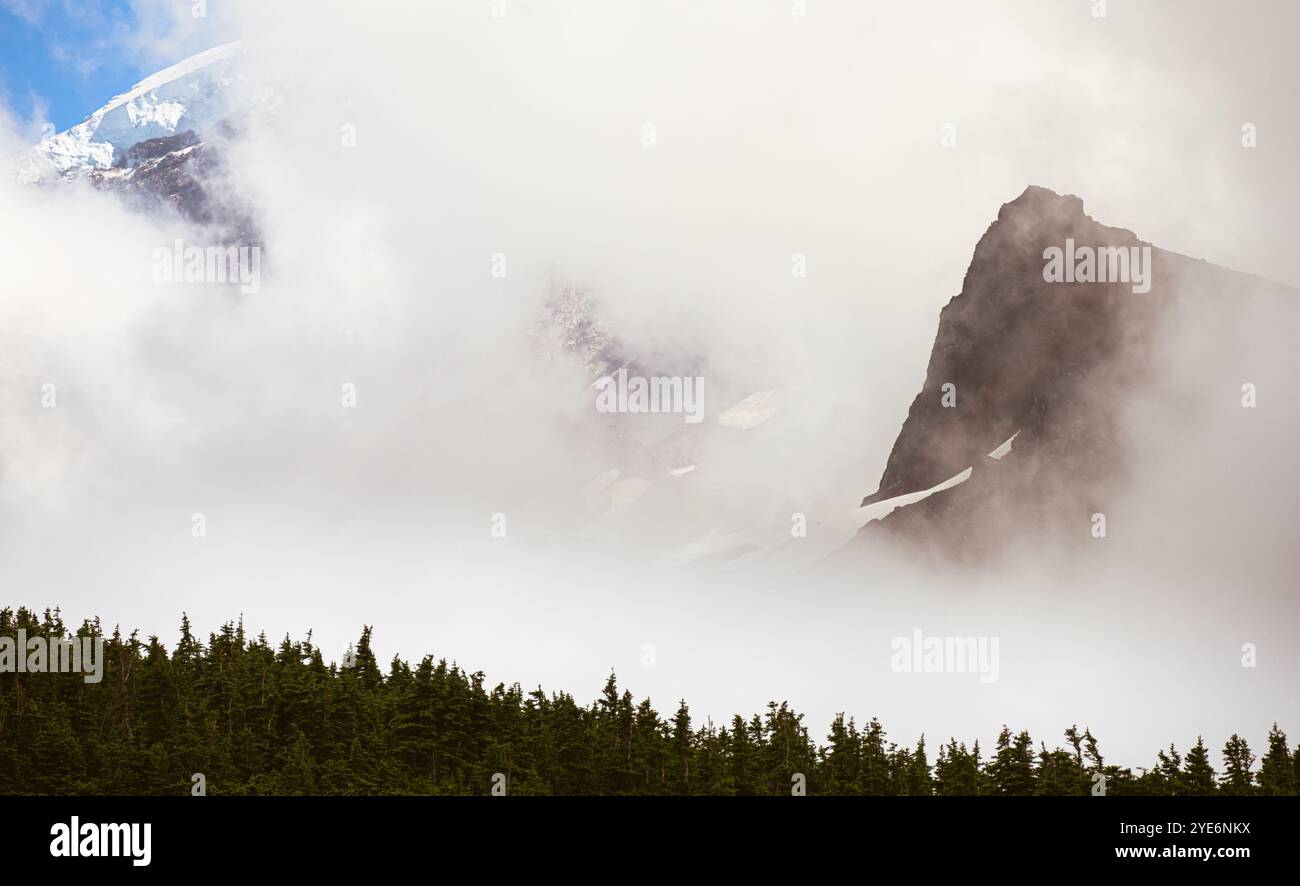 Echo Rock si distingue sotto Una sbirciatina del Monte Rainier attraverso la nebbia del Wonderland Trail Foto Stock