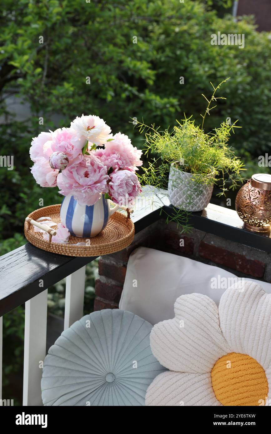 Bellissimi fiori di peonia rosa in vaso e piante in vaso su ringhiera del balcone all'aperto Foto Stock