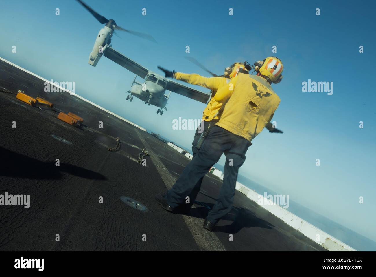 Un segnalatore di atterraggio della Marina degli Stati Uniti, guida un MV-22B Osprey del corpo dei Marines degli Stati Uniti assegnato al Marine Medium Tiltrotor Squadron (VMM) 362, Marine Aircra Foto Stock