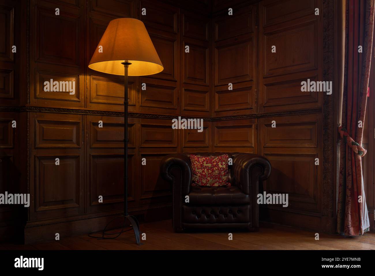 Interni suggestivi in una camera rivestita in legno con poltrona in pelle Foto Stock