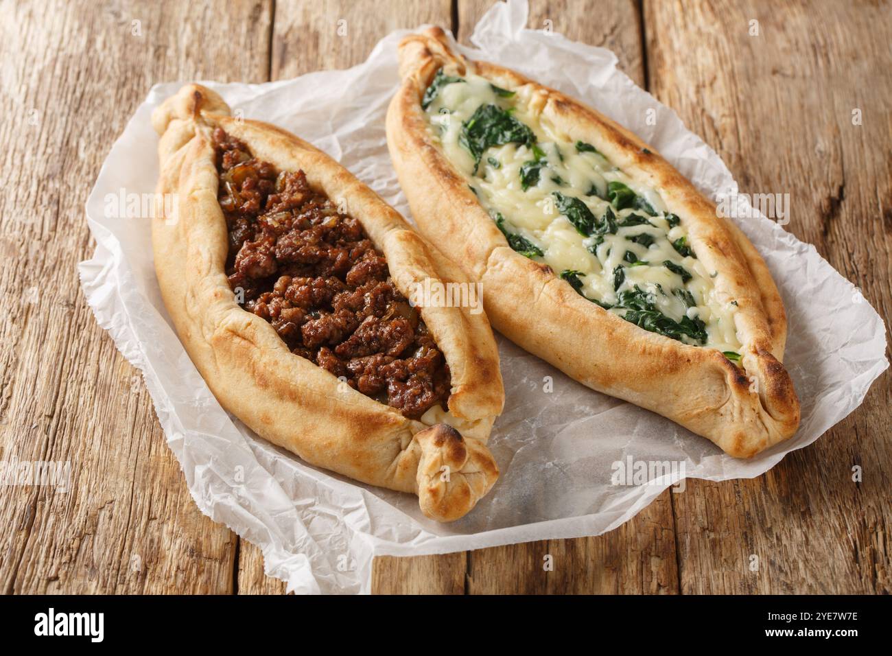 Pane piatto turco ripieno con una varietà di condimenti, tra cui formaggio, carne speziata e spinaci da vicino sul tavolo. Orizzontale Foto Stock