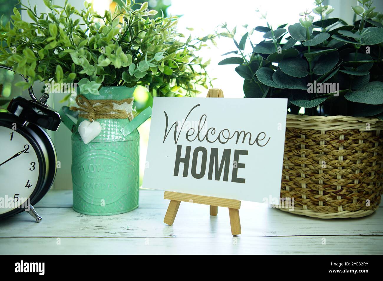 Benvenuto a casa citazioni testo su carta con cavalletto e sveglia sullo sfondo della finestra Foto Stock