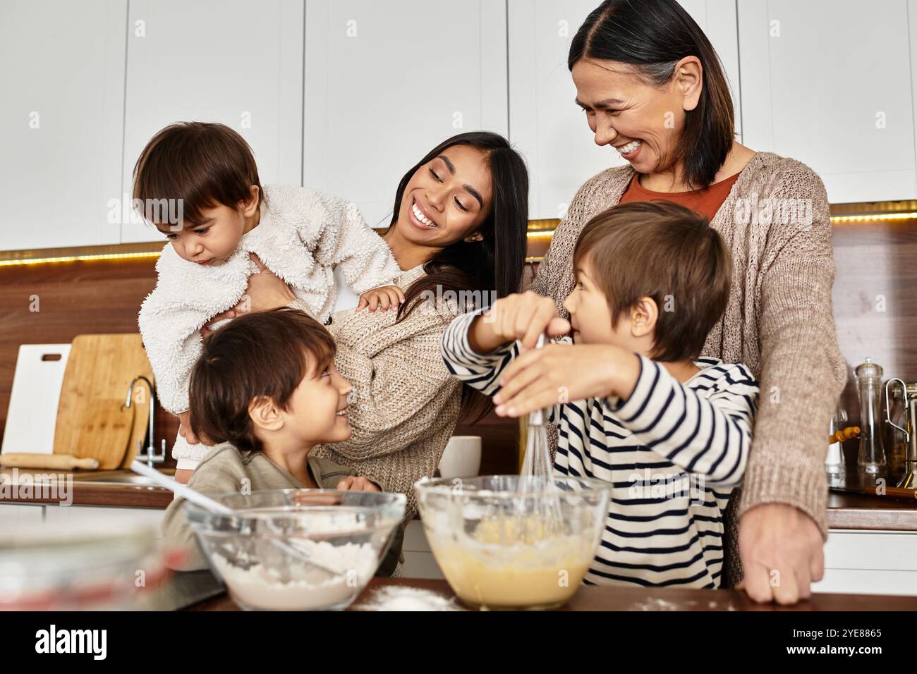 Una famiglia felice ama il calore della cucina insieme, creando prelibatezze natalizie per il Natale con i bambini impegnati. Foto Stock