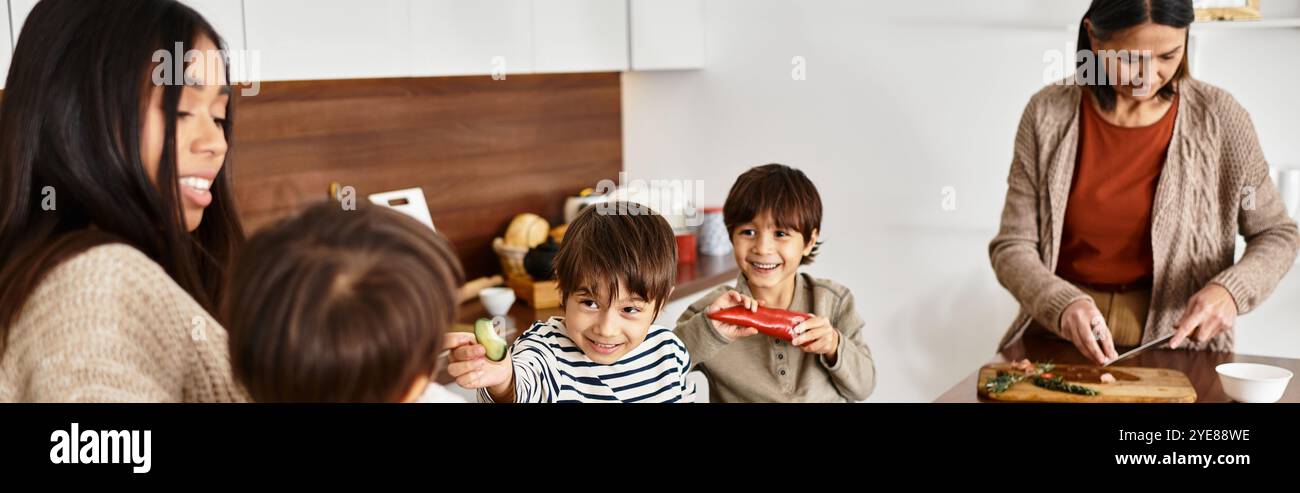 Una famiglia asiatica prepara deliziose prelibatezze natalizie nella sua moderna cucina con bambini allegri. Foto Stock