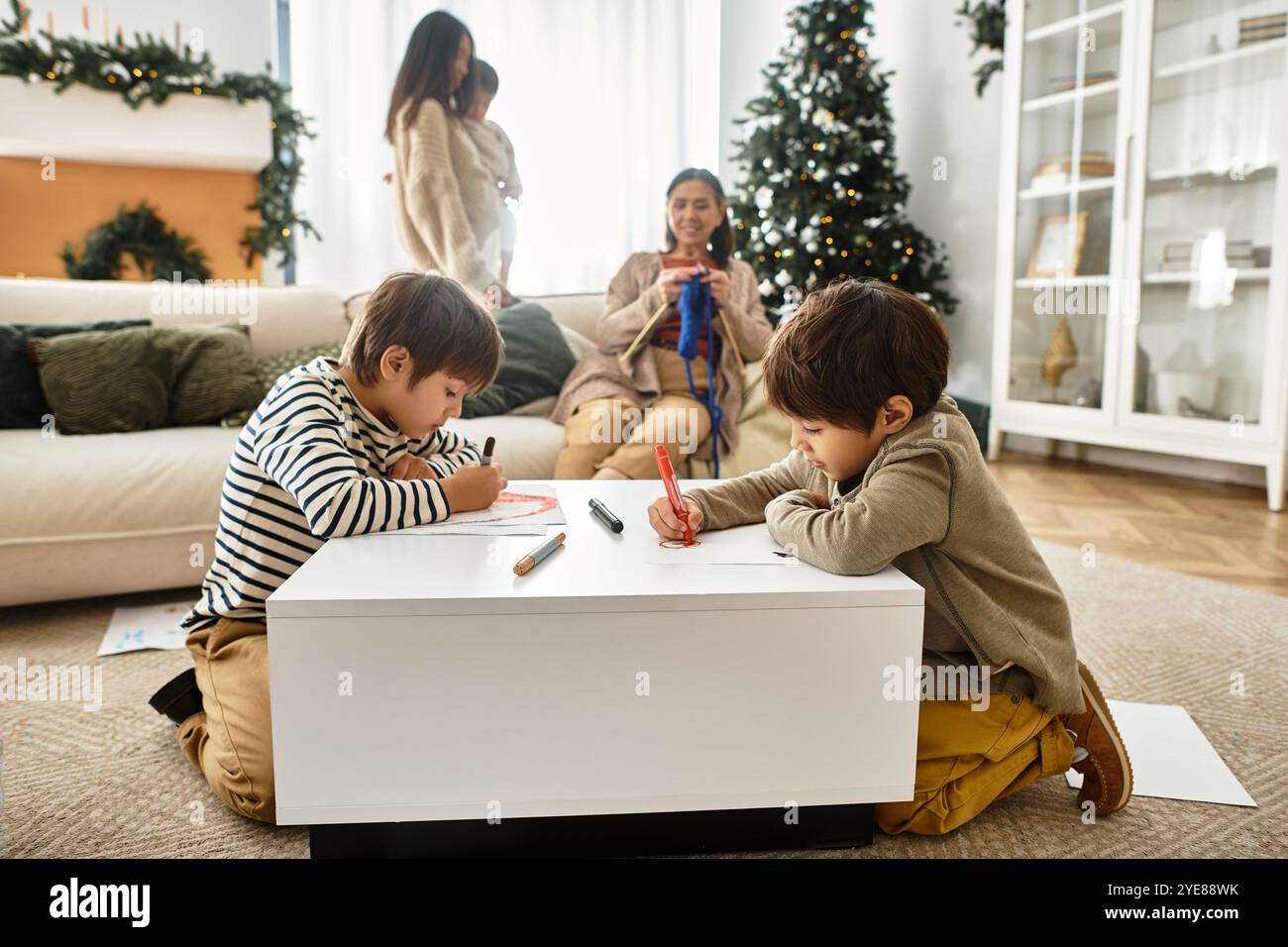 Una famiglia asiatica si riunisce intorno all'albero di Natale mentre i bambini colorano e gli adulti si immergono nello spirito festivo. Foto Stock