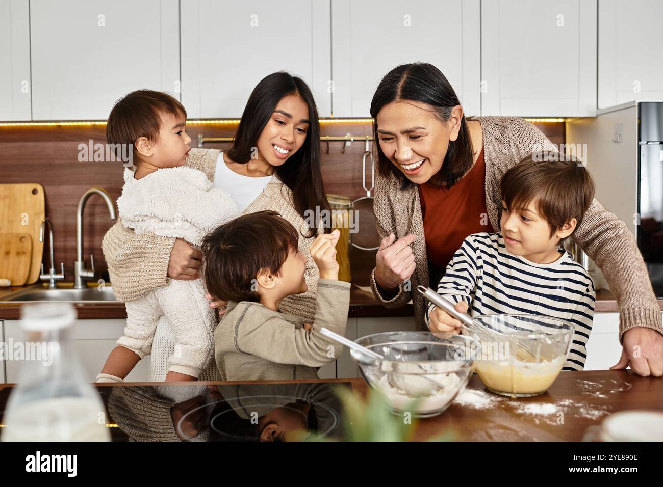 Una famiglia asiatica prepara con gioia le vacanze, con bambini che aiutano gli adulti in una cucina moderna. Foto Stock