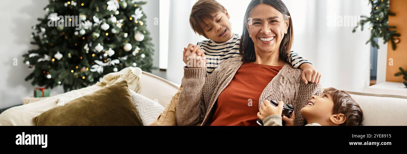 I membri della famiglia si riuniscono felicemente intorno al loro albero di Natale, condividendo risate e momenti festivi. Foto Stock