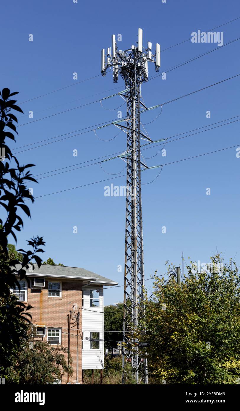 Charlotte, North Carolina, USA-ottobre 20, 2024: Alta torre cellulare ed elettrica in piedi nel cortile dell'edificio di appartamenti. Aspetto 10X16. Foto Stock
