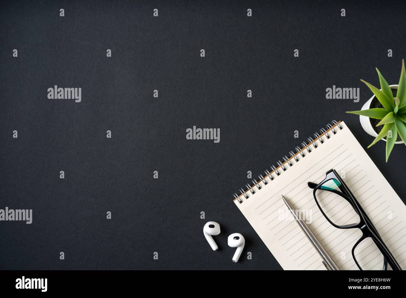 Vista dall'alto di notebook, cuffie, occhiali e penna a sfera su sfondo grigio scuro Foto Stock