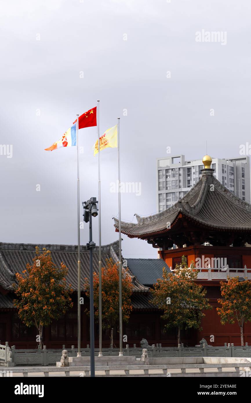 Bandiera nazionale cinese e altre bandiere che sventolano su palchi di fronte alla tradizionale architettura cinese Foto Stock