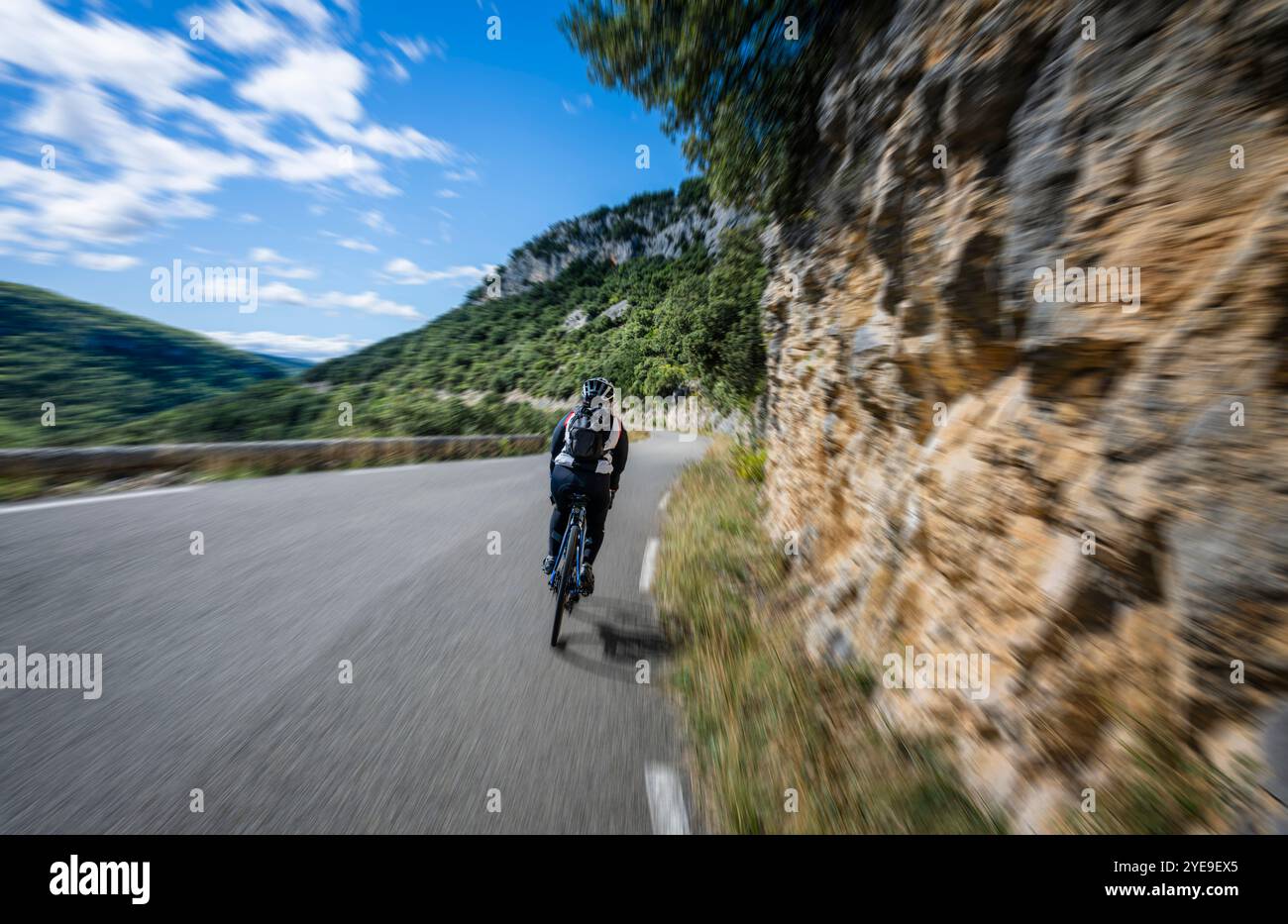 Ciclista matura che scende a velocità sostenuta attraverso le Gole della Nesque, Provenza, Francia. Foto Stock