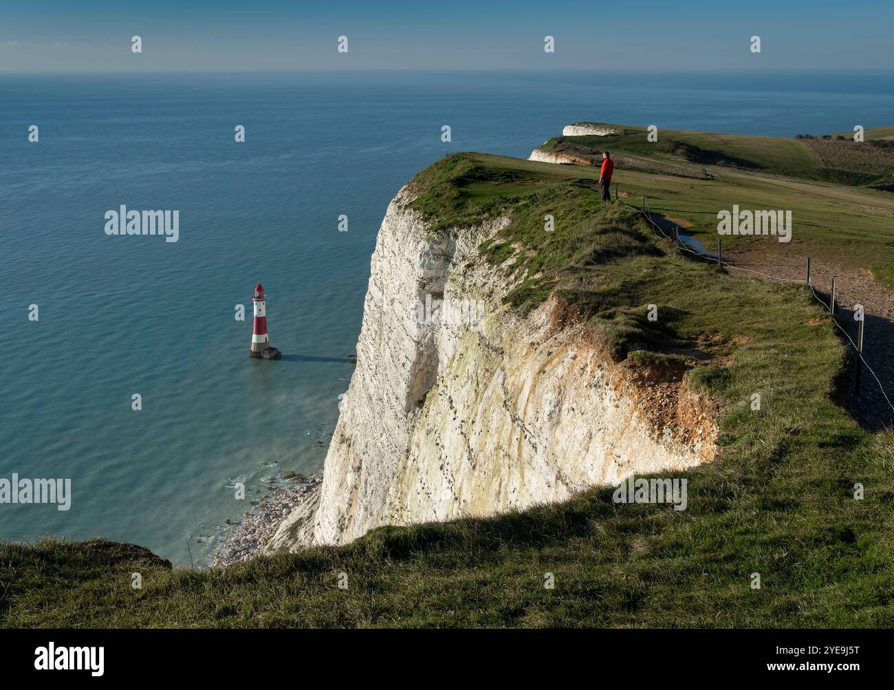 Uomo che guarda al faro di Beachy Head a Beachy Head, vicino a Eastbourne, South Downs National Park, East Sussex, Inghilterra, Regno Unito Foto Stock