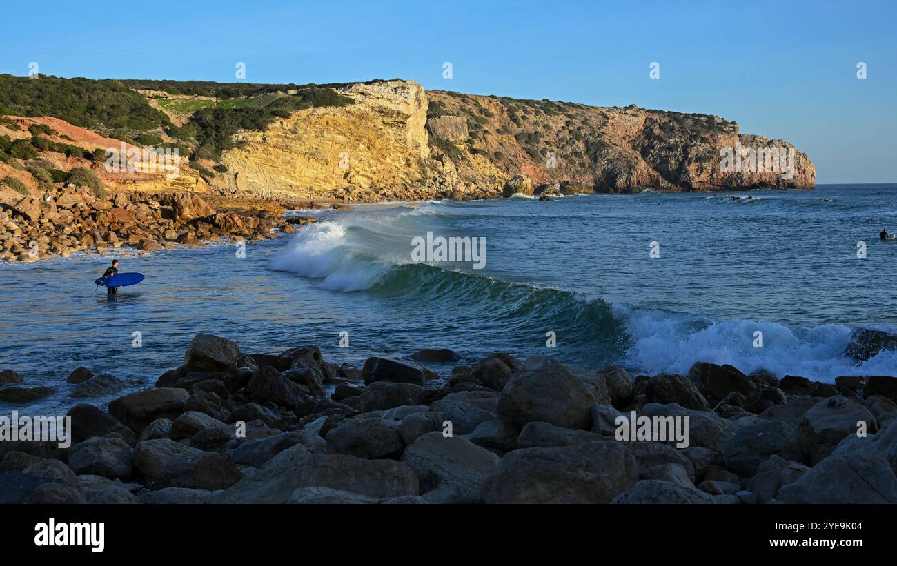 Surfisti pronti a prendere un'onda alla destinazione del surf Praia do Zavial, a Sagres, nella regione dell'Algarve, Portogallo; Raposeira, Faro, Portogallo Foto Stock