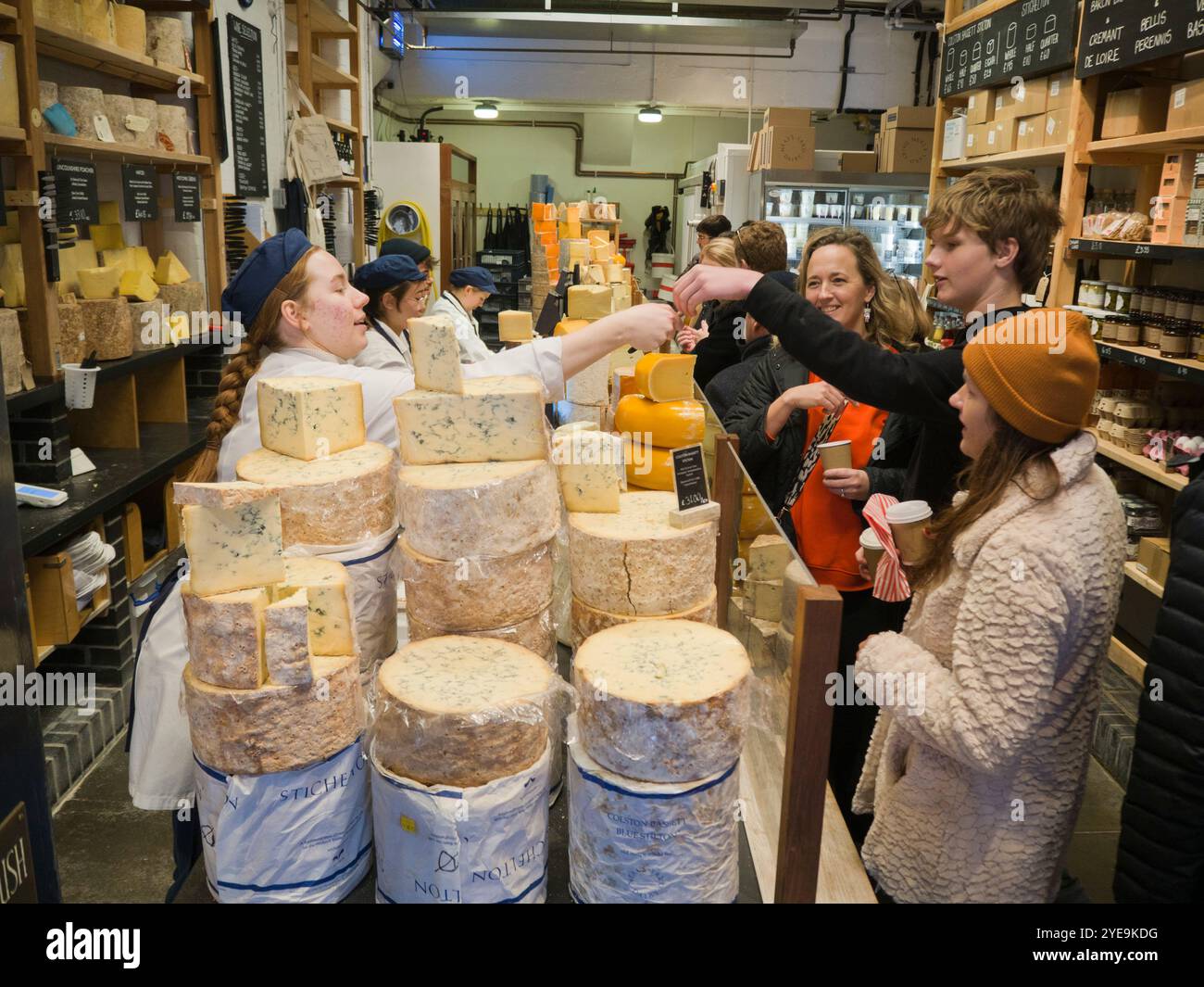 I clienti assaggiano formaggio presso il negozio Neal's Yard Dairy di Borough Market, Londra, Regno Unito; Londra, Inghilterra Foto Stock