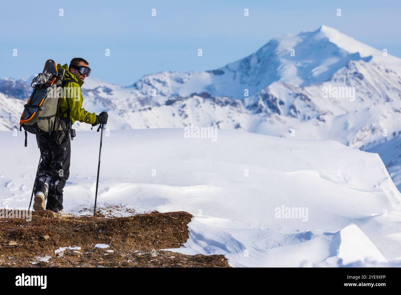 L'escursionista si avvicina a una deriva di neve sul Monte Pillsbury, nella catena dell'Alaska. Mount Silvertip è in lontananza; Alaska, Stati Uniti d'America Foto Stock