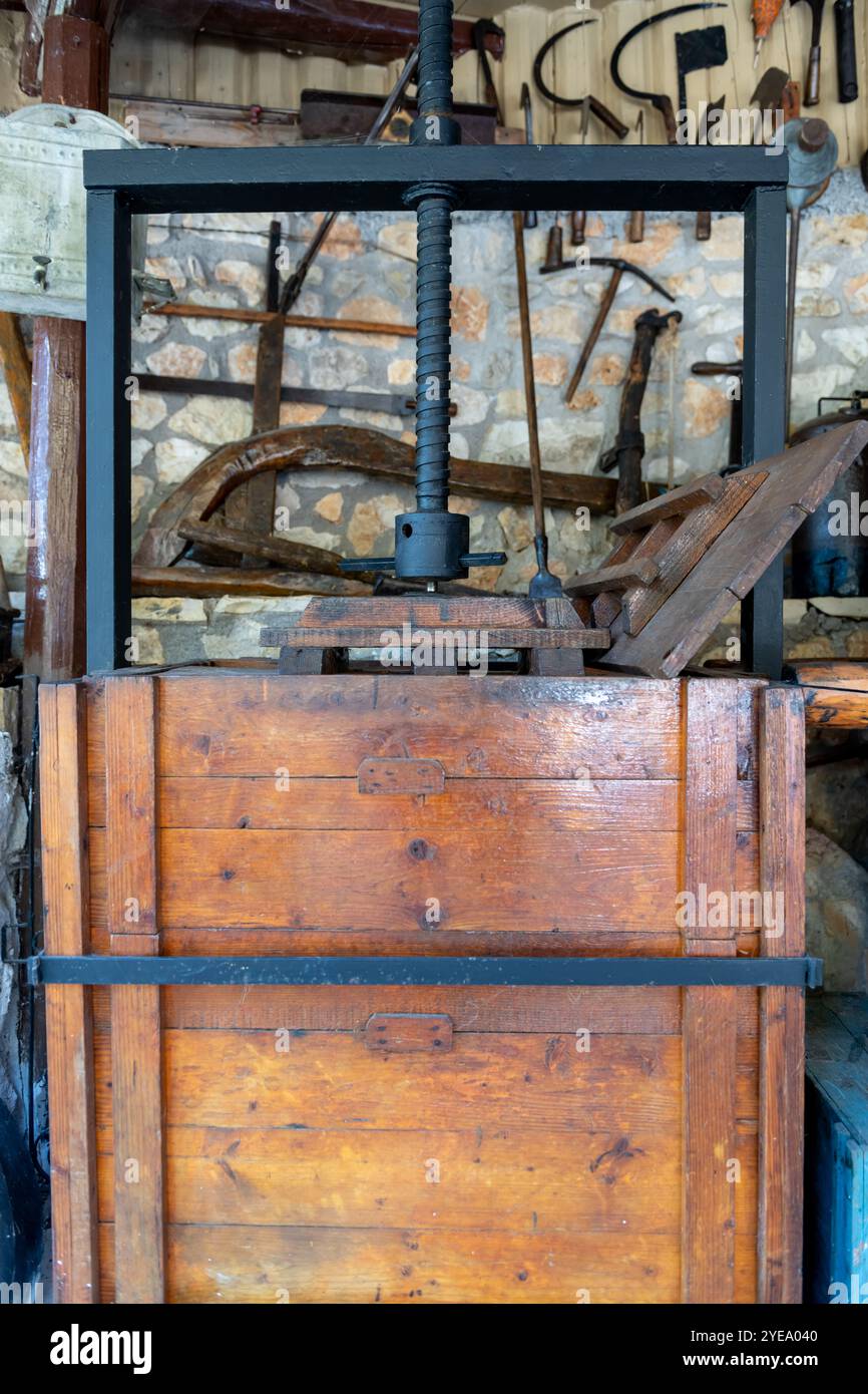 Una pressa in metallo vintage per la produzione di vino e olio d'oliva su un contenitore in legno rinforzato. Foto Stock