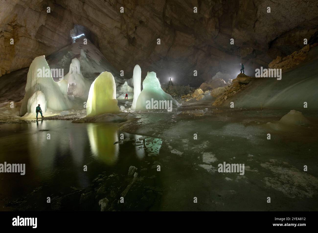Persone dell'Università di Innsbruck, in piedi all'interno di una grotta di ghiaccio illuminata situata nelle Alpi europee, che svolgono ricerche scientifiche sul ghiaccio... Foto Stock