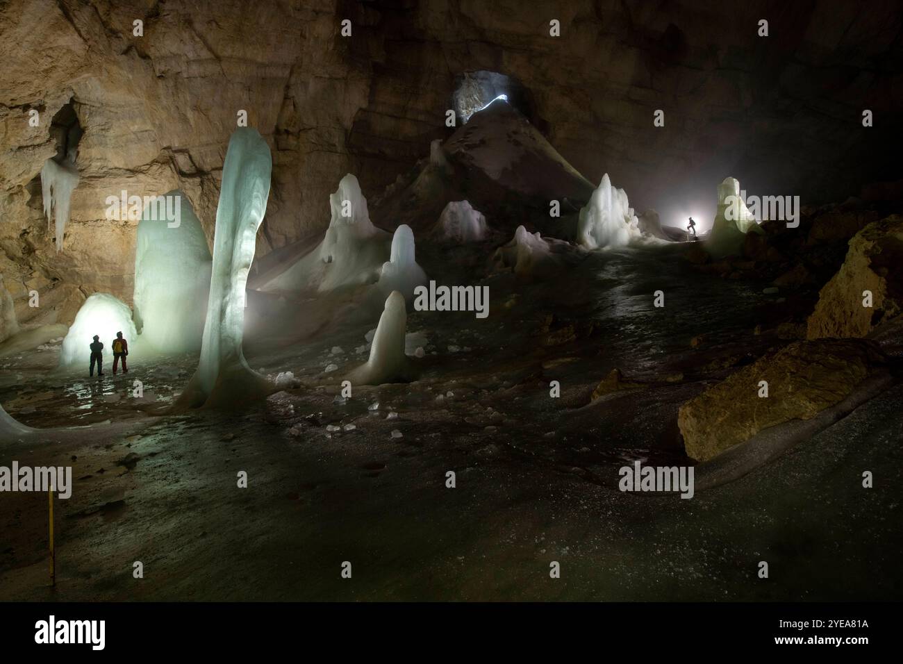 Persone dell'Università di Innsbruck, in piedi all'interno di una grotta di ghiaccio illuminata situata nelle Alpi europee, che svolgono ricerche scientifiche sul ghiaccio... Foto Stock