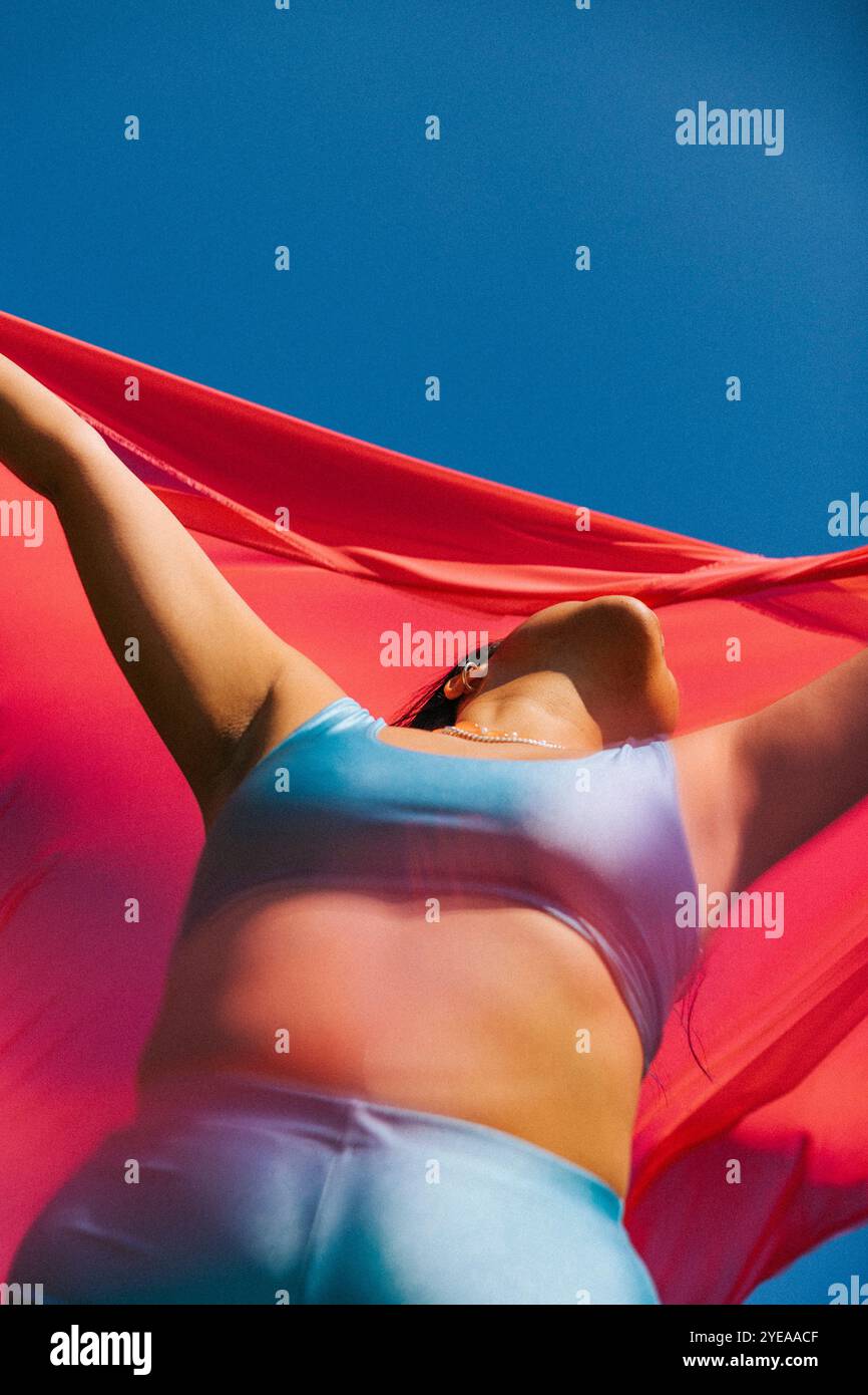 Vista ad angolo basso della giovane donna che tiene il dupatta rosso sotto il cielo limpido Foto Stock