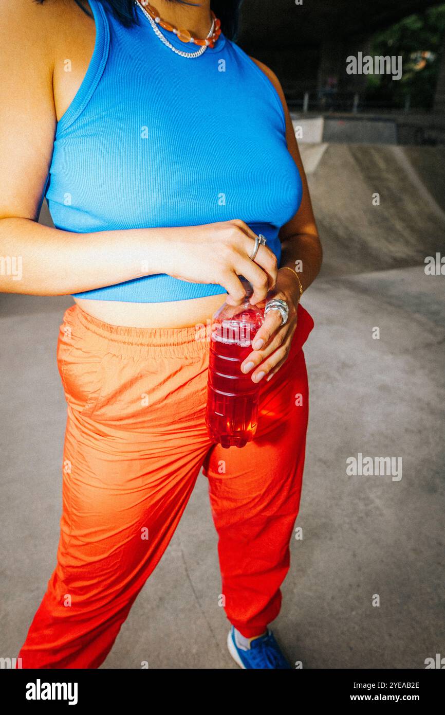 Sezione centrale ad alto angolo di una giovane donna che tiene in mano una bottiglia di bevanda energetica Foto Stock